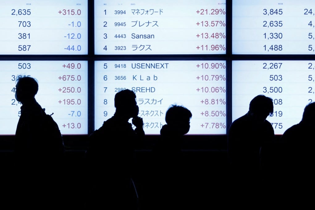 People are silhouetted as they walk past an electric stock quotation board outside a brokerage in Tokyo on October 18, 2022. Photo: Reuters