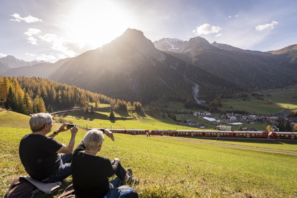Onlookers watch a Rhaetian Railway train on its way to set a world record for longest passenger train, in Berguen, Switzerland on Saturday. Photo: EPA-EFE / Yanik Buerkli Tilt Shift Linse