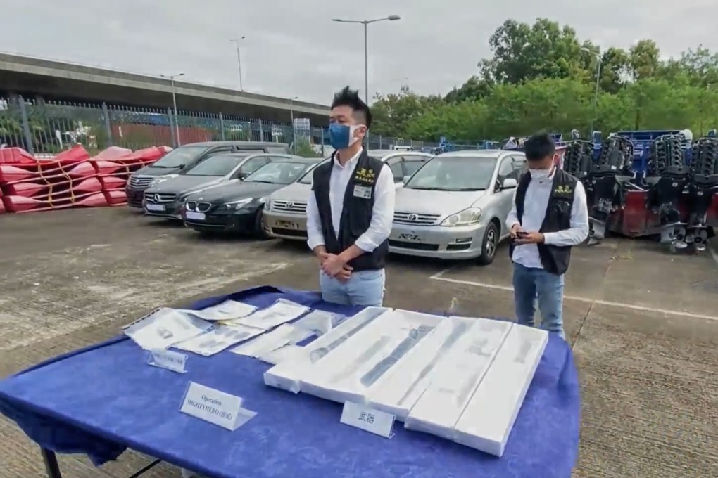 Police officers display items seized during their operation, with the recovered vehicles in the background. Photo: Handout