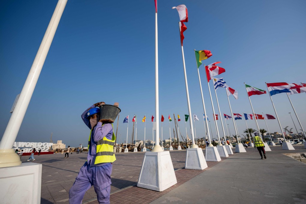 A worker carries a bucket of building materials past the World Cup stadium in Doha. Photo: AFP