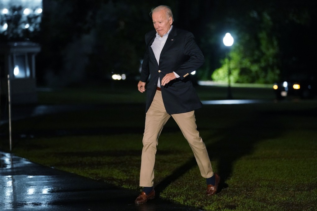 President Joe Biden navigates the muddy grass on a rainy night on the South Lawn of the White House. Photo: AP