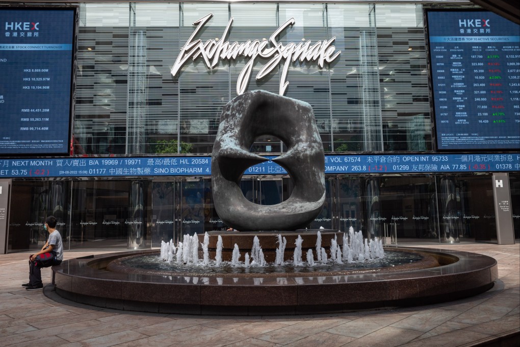 A man sits in front of electronic billboards displaying the Hang Seng Index in Hong Kong on August 29, 2022. Photo: EPA-EFE