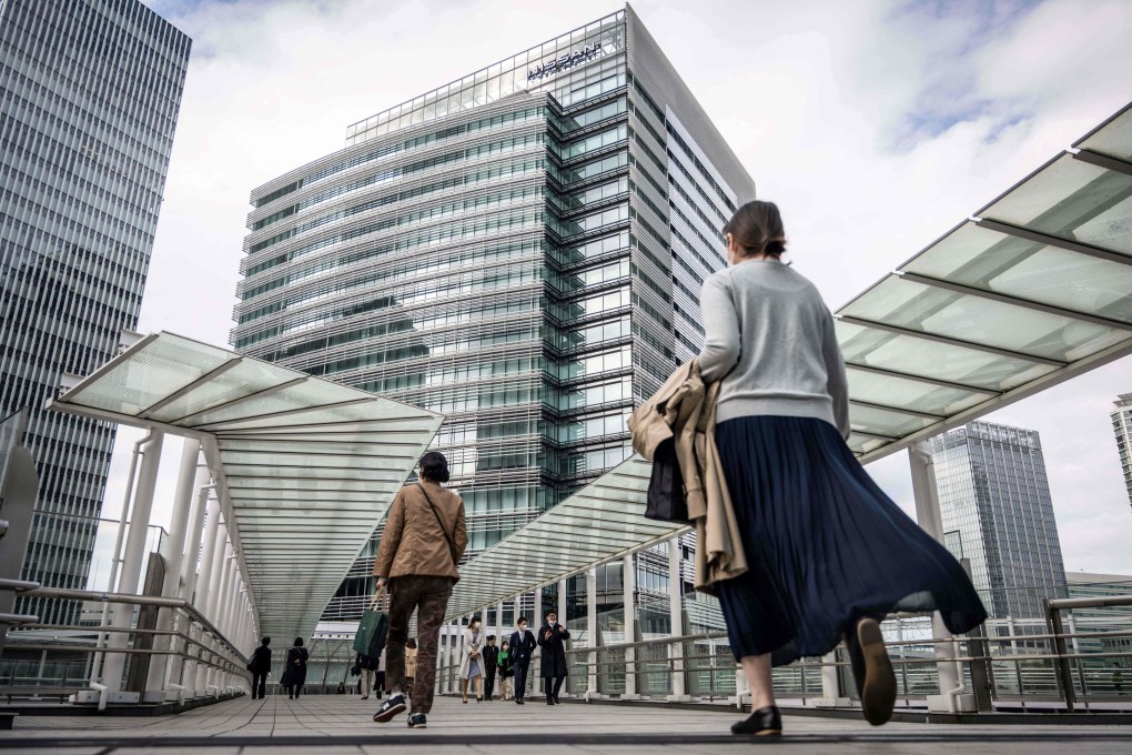 People walking near the head office (C) of Japanese automaker Nissan Motor in Yokohama. Photo: AFP