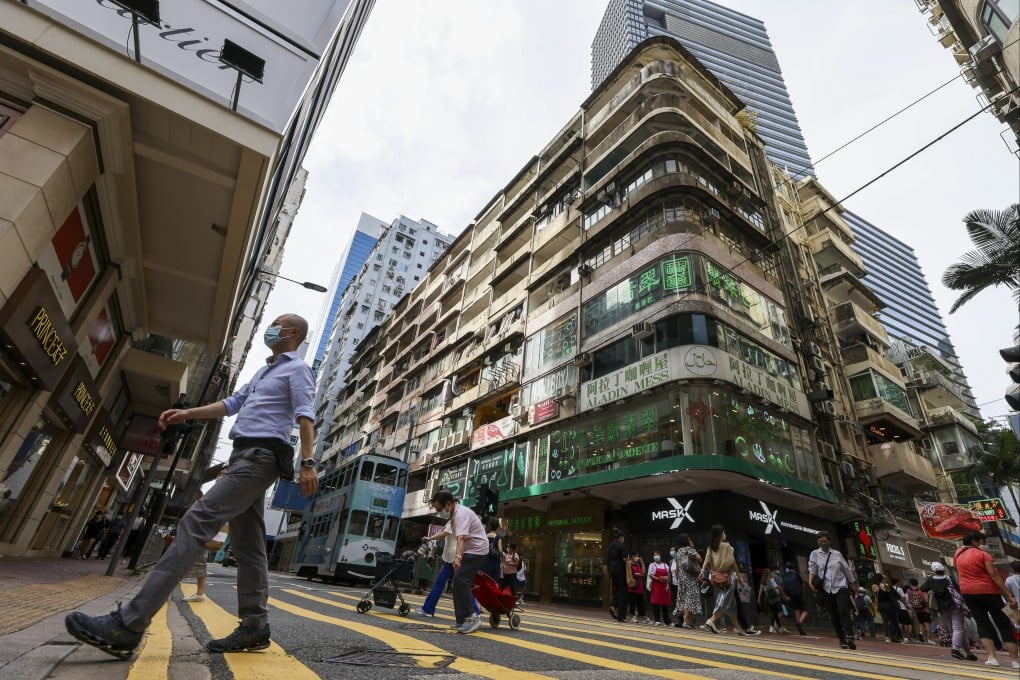 Pedestrians cross a street in Causeway Bay near a building subject to a compulsory sale on May 30. Photo: Nora Tam
