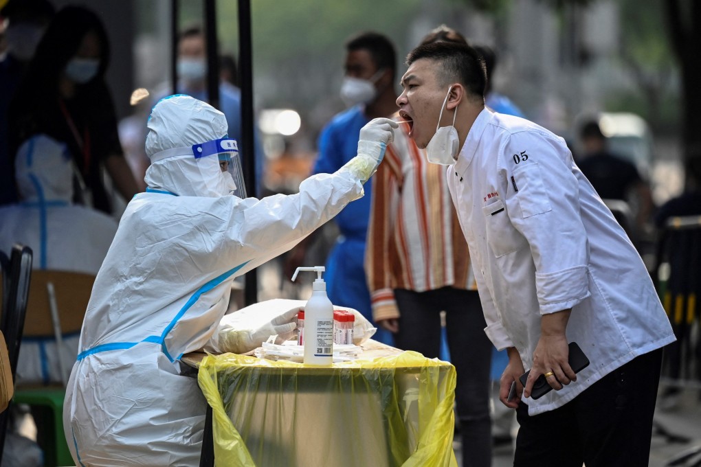 A health worker takes a swab sample from a man to be tested for Covid-19 at a makeshift testing site outside a shopping mall in Beijing on June 15, 2022. Such tests can be a daily occurrence in zero-Covid China. Photo: AFP