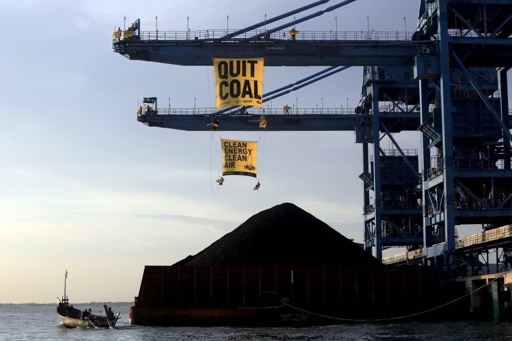 Indonesian Greenpeace activists hang banners as they block the loading of coal at a power plant in Cirebon, Indonesia, on May 15, 2016. Photo: EPA