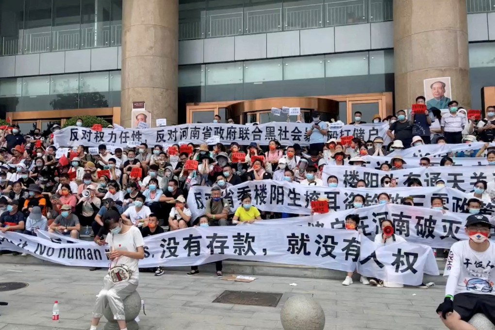 Demonstrators hold banners during a protest over the freezing of deposits by rural banks in Henan province. Photo: Reuters