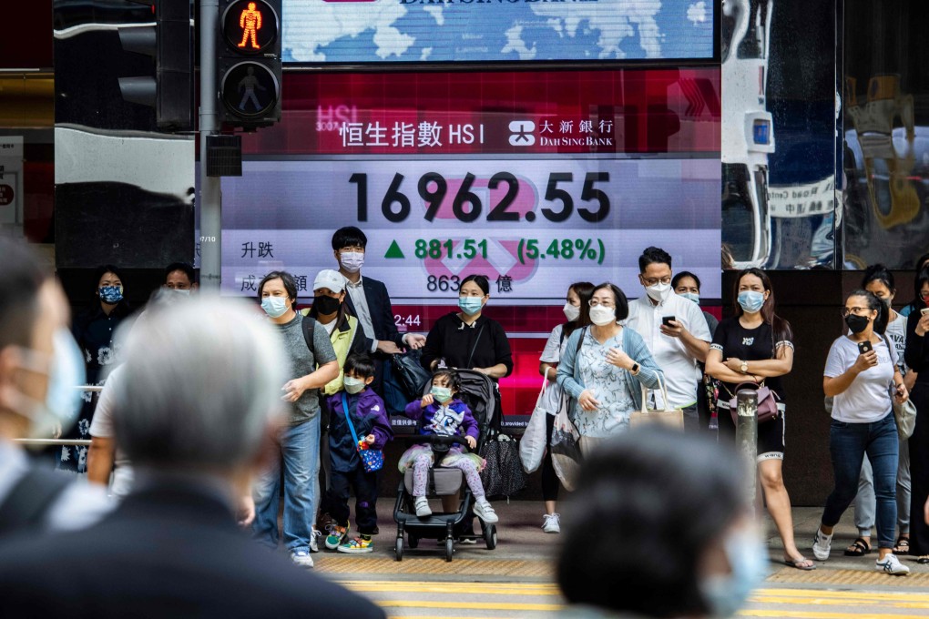 People wait to cross a street past an electronic sign showing the Hang Seng index in Hong Kong on Friday. Stocks surged as investors bet on the China reopening theme. Photo: AFP