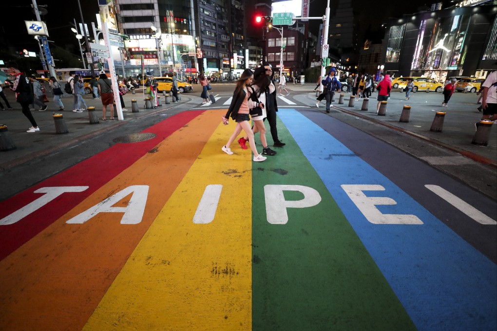 People walk across a pedestrian lane painted in the colours of the rainbow flag in Taipei on October 14, 2019. The government has earned praise for liberal policies like gay marriage, but seems much less enthusiastic about tackling serious issues such as crime. Photo: EPA-EFE
