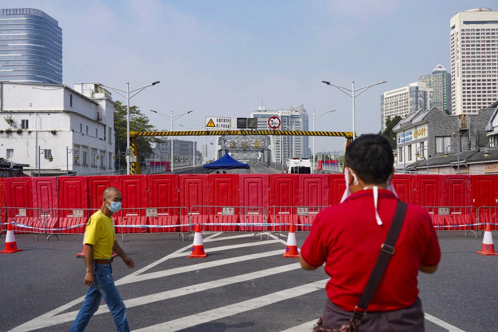 Residents wearing masks pass by barriers used to form a security checkpoint in Haizhu district in Guangzhou on Friday. Photo: AP