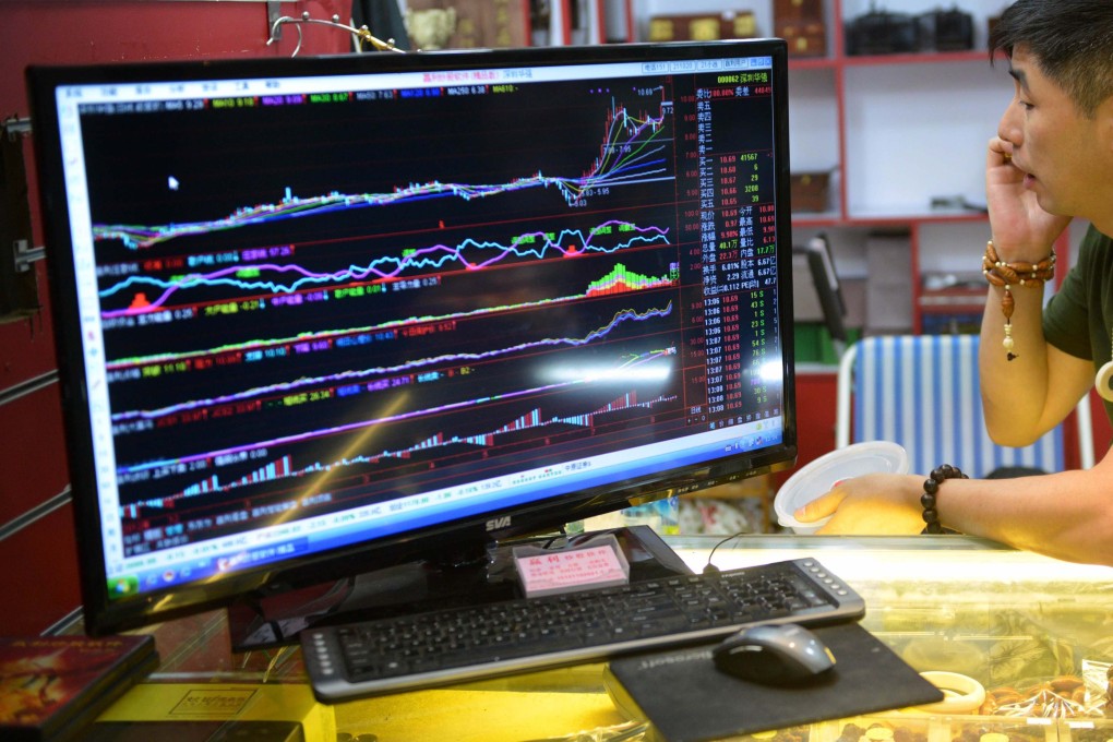A vendor talks on his phone next to a screen showing stocks data at a stall in a market in Shanghai. Photo: AFP