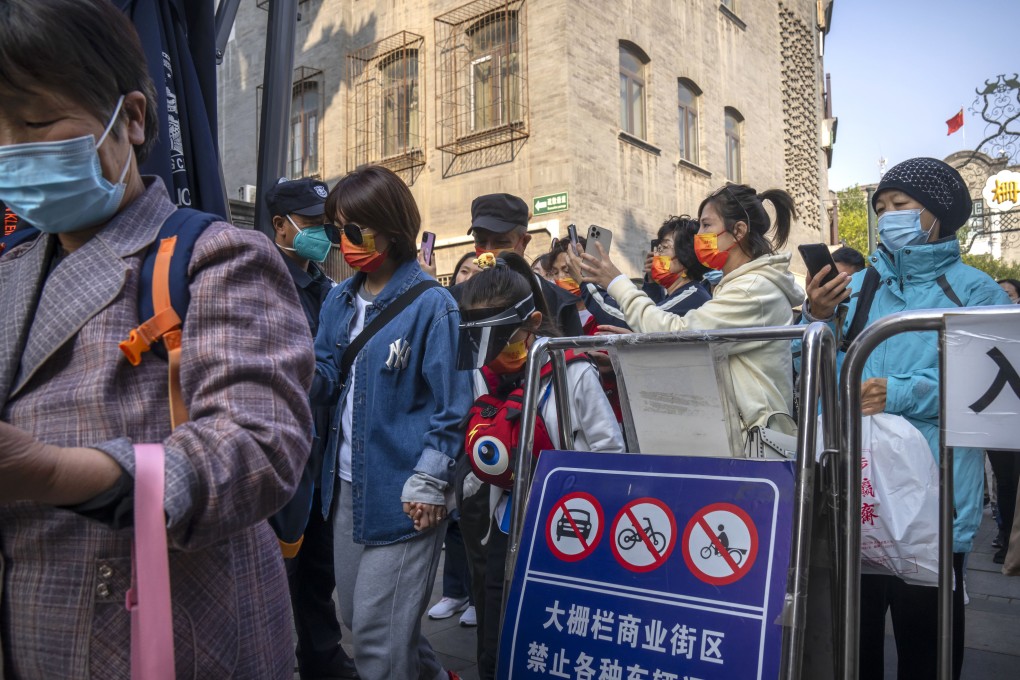 Visitors show their health-check app for scanning as they enter a tourist street in Beijing. China is easing restrictions on travel between provinces. Photo: AP