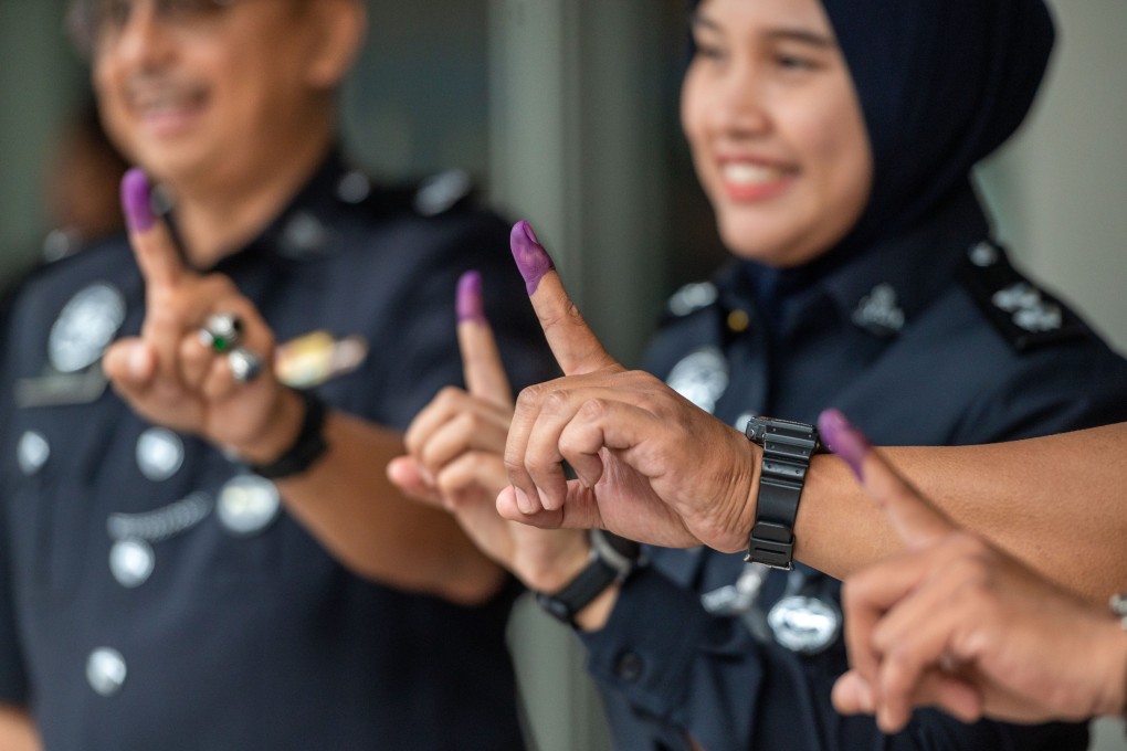 Malaysian police officers show their inked fingers after casting their votes in early voting for the November 19 general election. The ink, which takes a few days to wear off, is aimed at helping prevent people turning up and trying to vote again. Photo: Xinhua