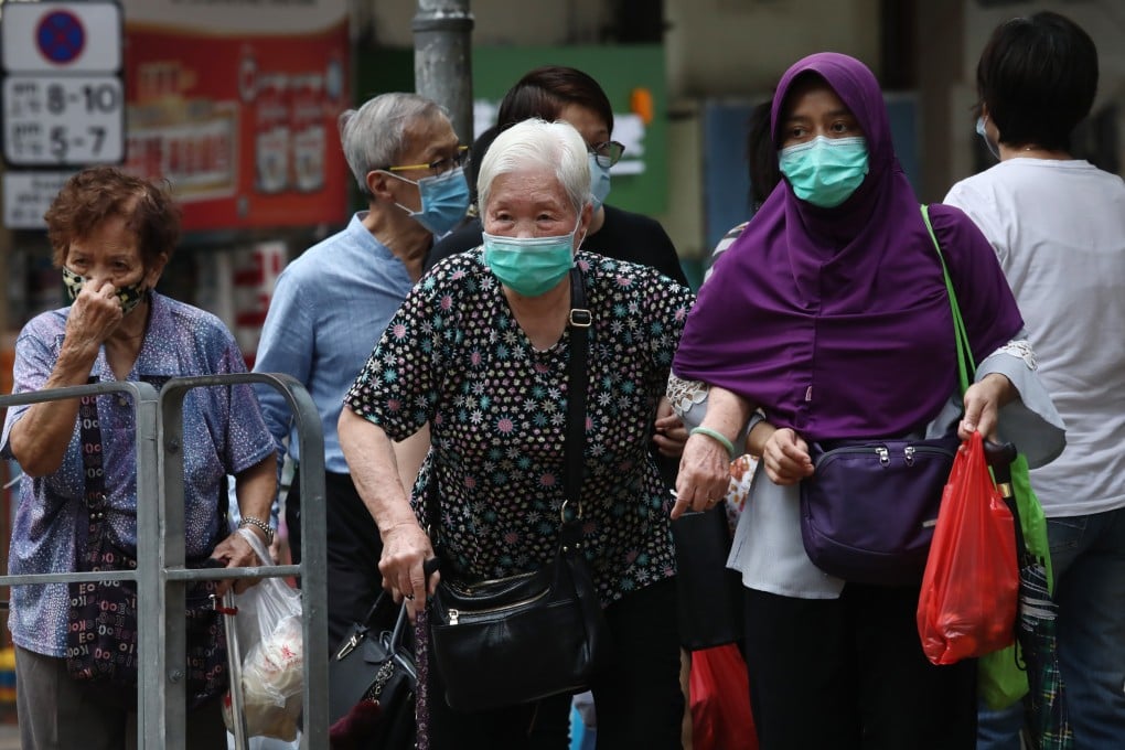 A domestic worker crosses the road with a senior citizen in Sai Ying Pun. Migrant domestic workers who help care for Hong Kong’s young and old should be encouraged to take breaks during the day and connect with their children back home. Photo: Jonathan Wong