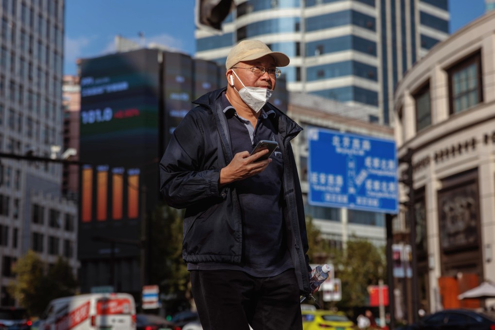 epa10262578 A man walks next to the large screen showing stock and economic data in Shanghai in October 2022. Photo: EPA-EFE