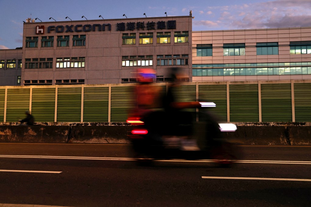 People riding a motorcycle pass the logo of Foxconn Technology Group outside the company’s building in Taipei on November 10, 2022. Photo: Reuters