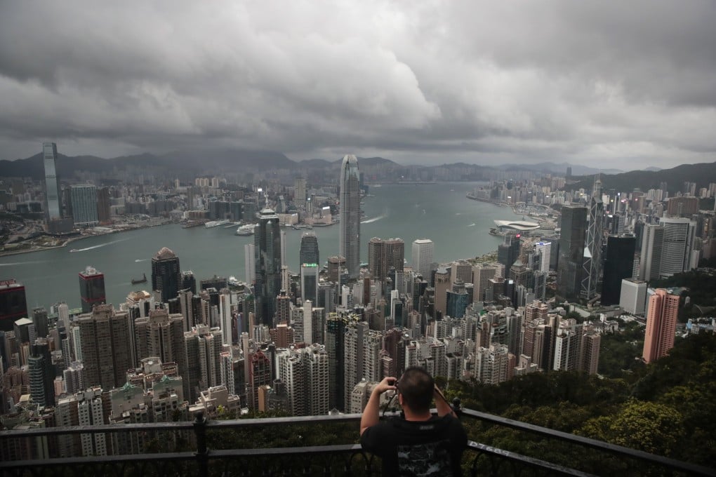 FILE - A visitor sets up his camera in the Victoria Peak area to photograph Hong Kong’s skyline, Sept. 1, 2019. A tropic storm and absences of VIP guests have cast a shadow over Wednesday’s planned financial conference meant to help Hong Kong restore its image as a financial hub and destination for business travel. (AP Photo/Jae C. Hong, File)