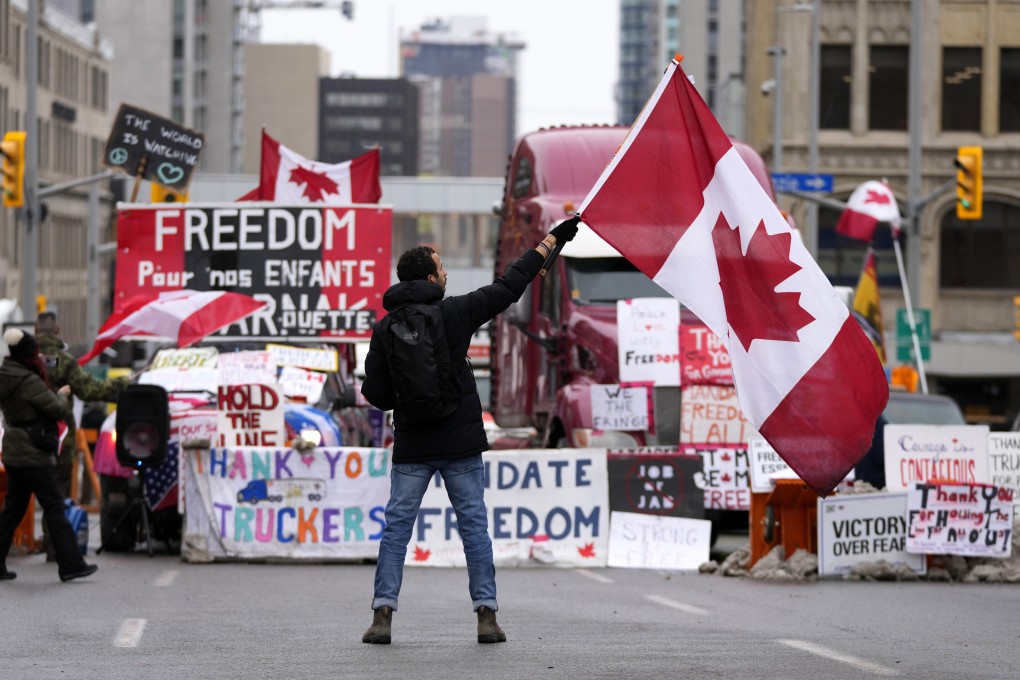 A protester waves a Canadian flag in front of parked vehicles in Ottawa in February. Photo: The Canadian Press via AP