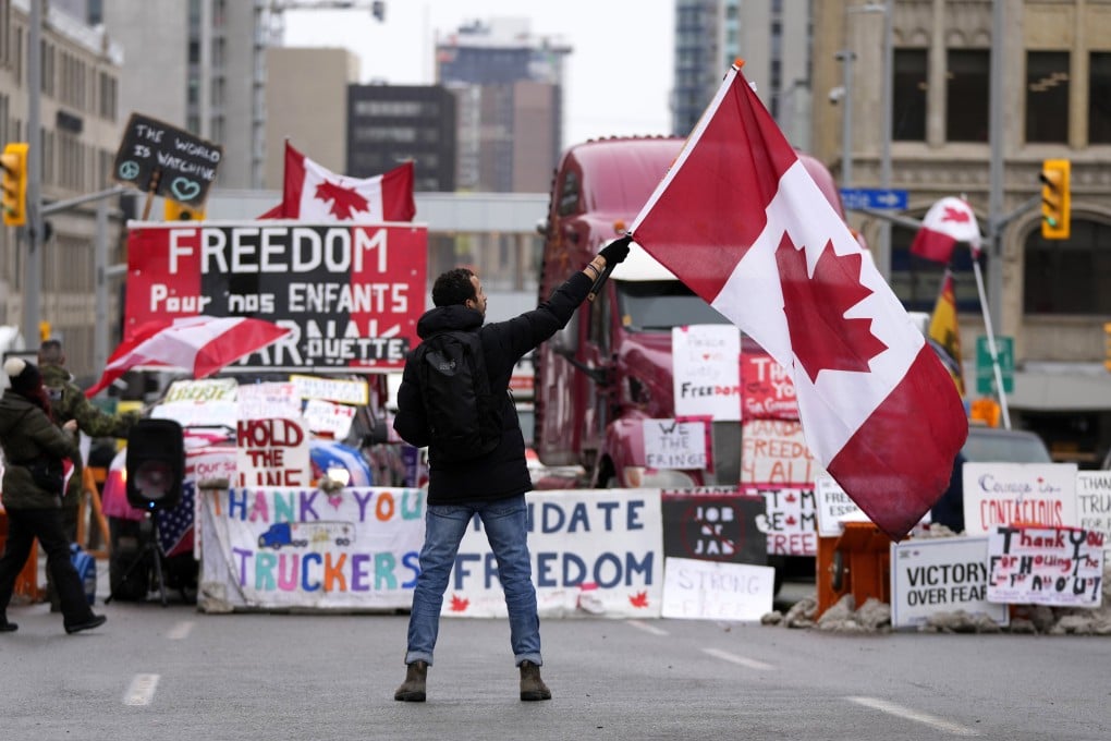 A protester waves a Canadian flag in front of parked vehicles in Ottawa in February. Photo: The Canadian Press via AP