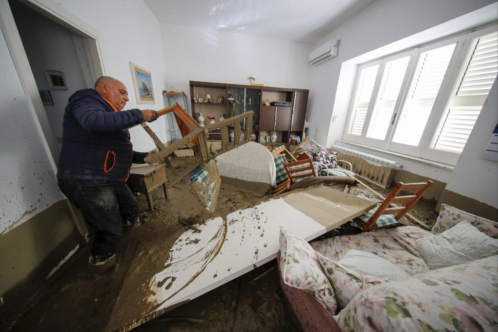 A man walks among mud and debris in his home on Sunday after heavy rain triggered landslides that killed at least 2 on the Italian island of Ischia. Photo: AP