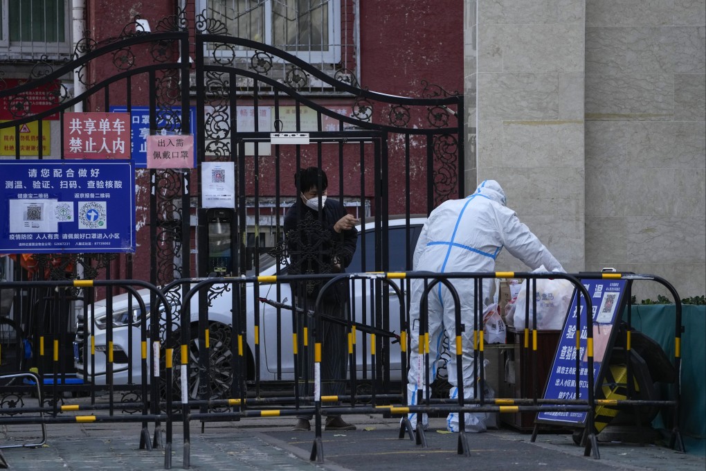 A resident of a fenced-off residential compound asks a health worker to help pick up his groceries, in Beijing on Sunday. Photo: AP