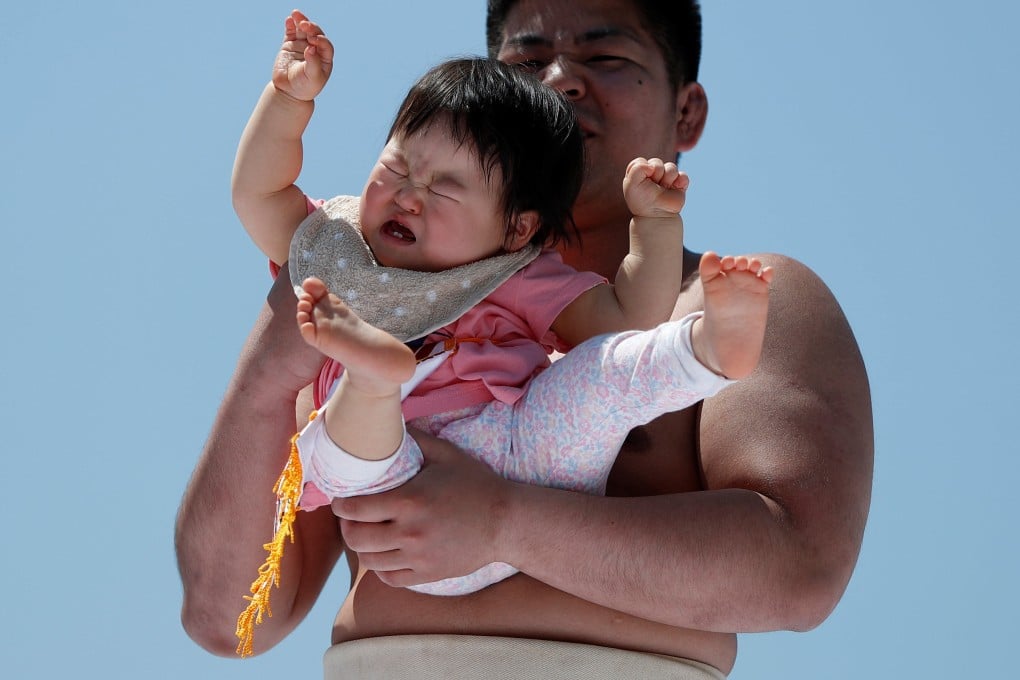 An amateur sumo wrestler holds a baby during a baby crying contest at a temple in Tokyo in 2018. The annual number of births in Japan is projected to fall to 740,000 by 2040. Photo: Reuters