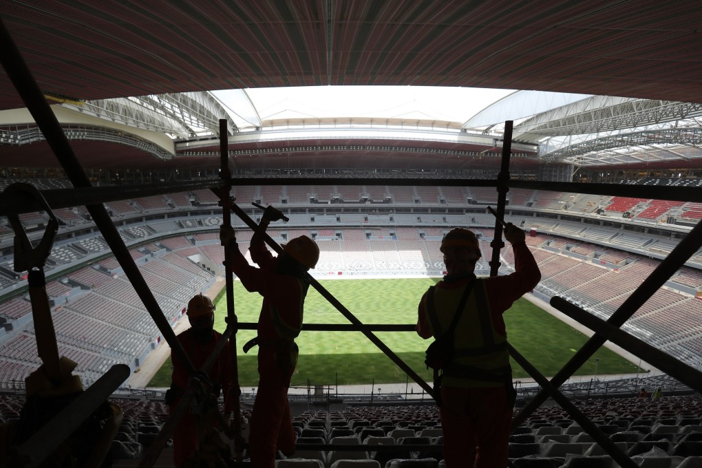 Labourers remove scaffolding at the Al Bayt stadium in Al Khor, Qatar. Migrant labourers who built Qatar’s World Cup stadiums often worked long hours under harsh conditions and were subjected to discrimination, wage theft and other abuses as their employers evaded accountability. Photo: AP