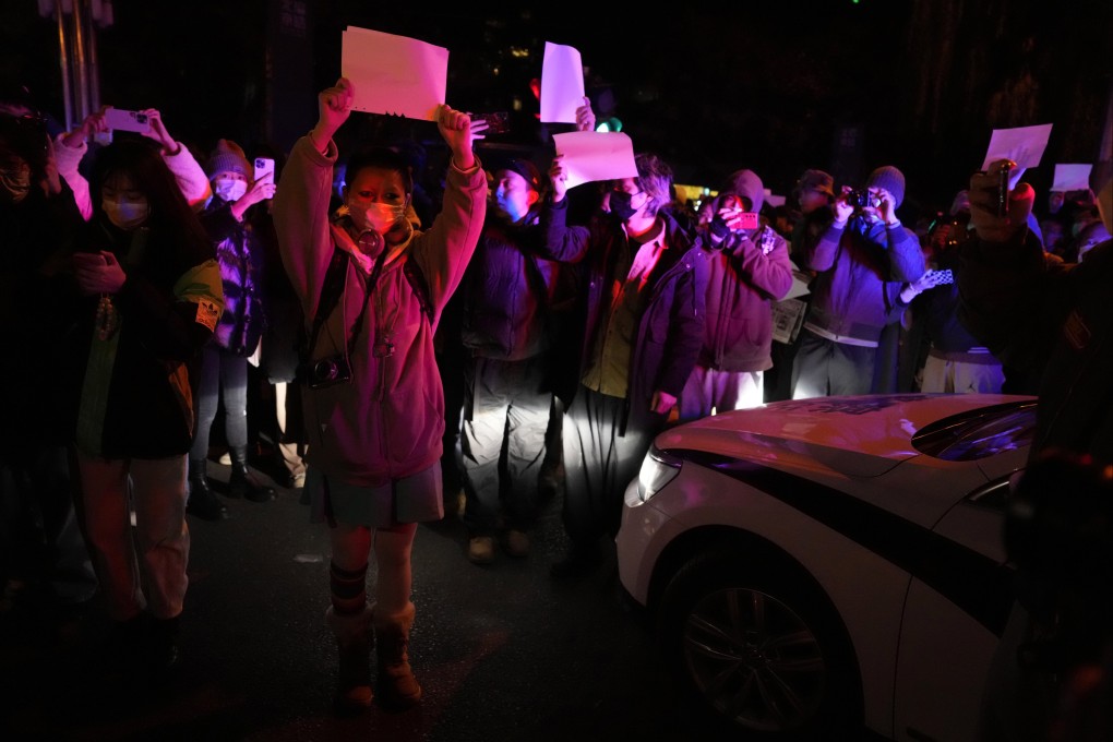 Protesters hold up blank sheets of paper and chant slogans as they march in Beijing on Sunday. Photo: AP