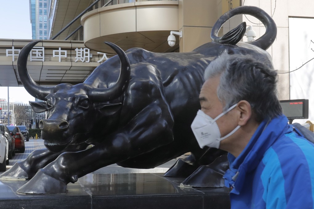 A man walks by a bronze sculpture of a bull in the central business district in Beijing, in March 2020. Photo: EPA-EFE