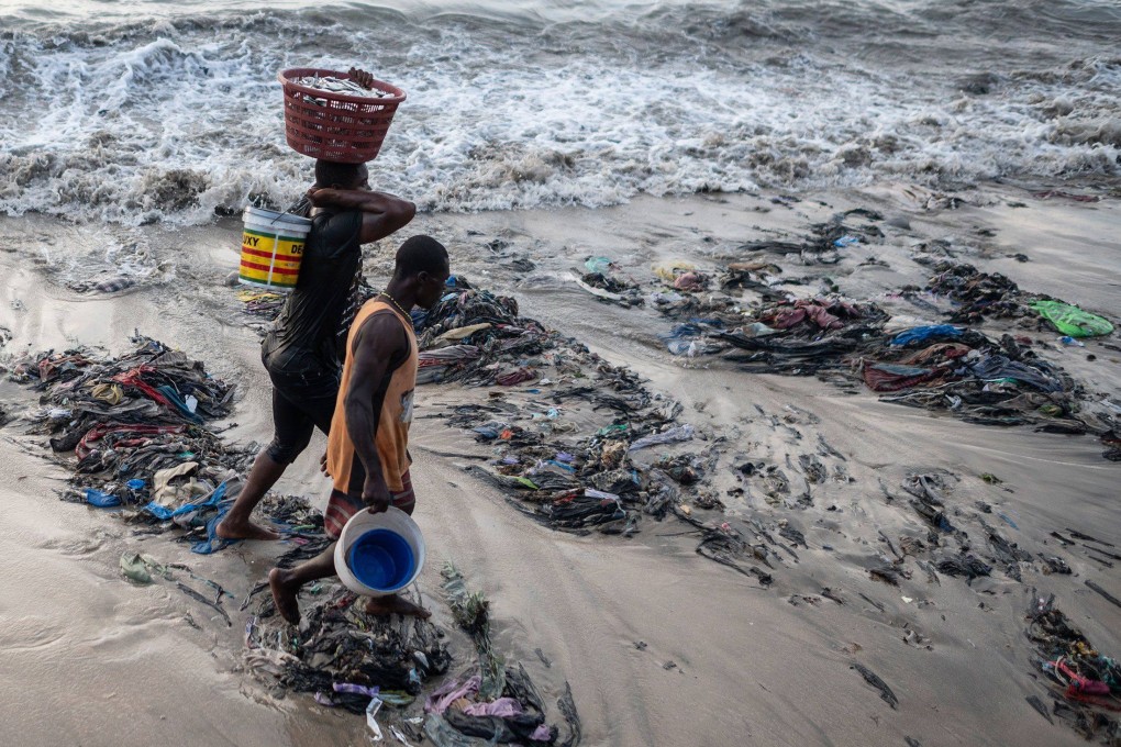 Fishermen walk across a beach strewn with rubbish including discarded clothes, many of which fall in the fast-fashion category, at Chorkor beach, near Accra, Ghana. Photo: Andrew Caballero-Reynolds / Bloomberg