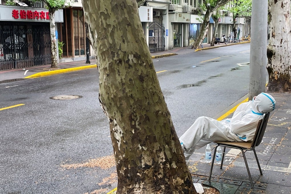 A community health worker rests by the roadside in a locked down area of Shanghai during a Covid-19 outbreak. Photo: Reuters