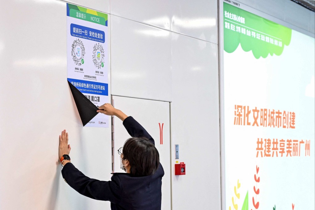 A subway staff member removes a poster for a Covid-19 health code used on entering the subway in Guangzhou on December 7 following the easing of Covid-19 restrictions in the city. Photo: AFP