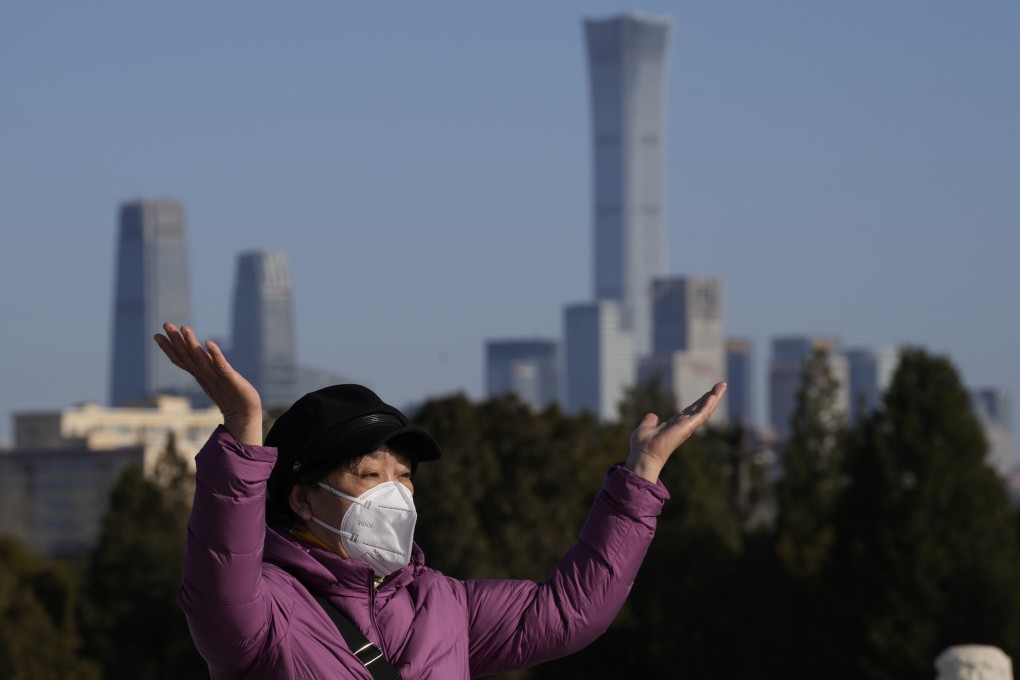 A woman poses for a photo in the Temple of Heaven Park, in Beijing, with the city skyline in the background, on December 8. Photo: AP