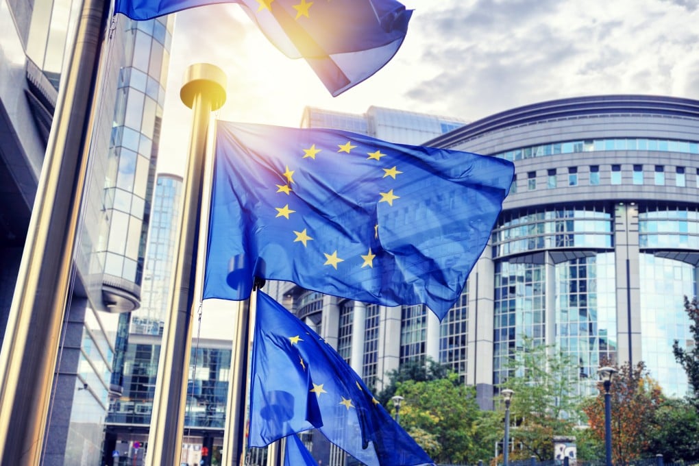 EU flags wave in front of the European Parliament building in Brussels, Belgium.