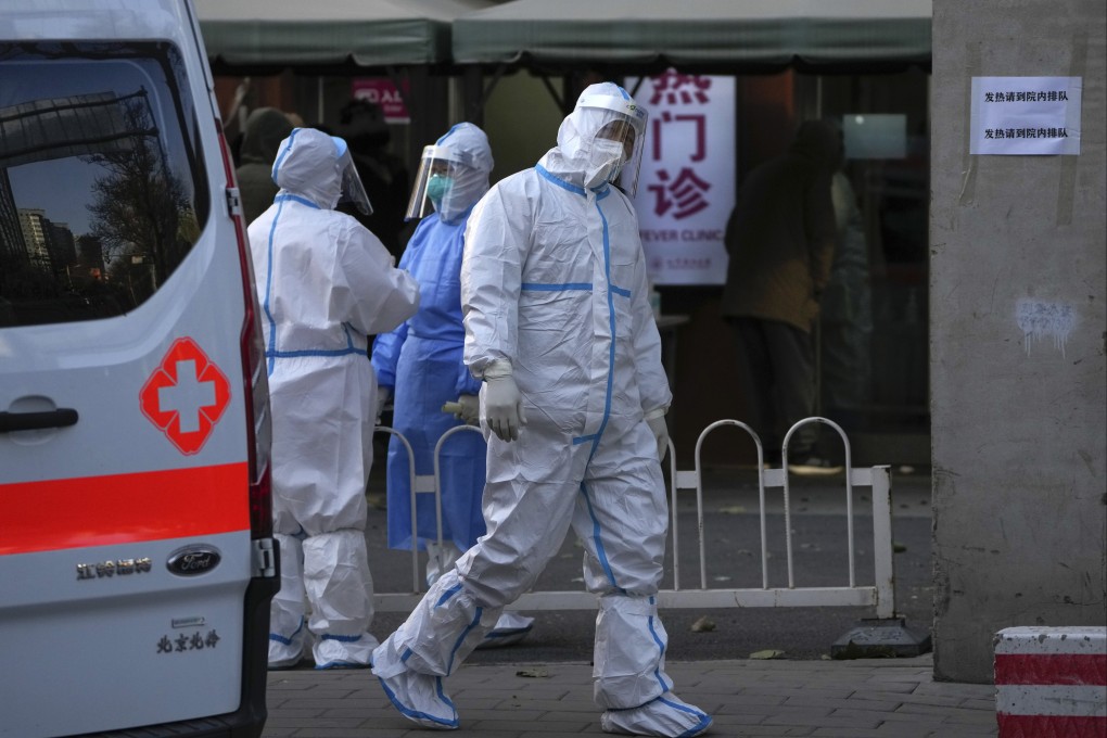 As Beijing residents wait to enter the fever clinic of a hospital in Beijing on Tuesday, an ambulance worker in protective gear and medical workers stands by. Photo: AP