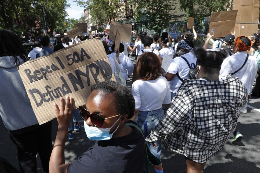 A woman holds a sign calling for the repeal of a law that shields police misconduct records from public view, and calling for defunding the New York Police Department. Photo: AP/File