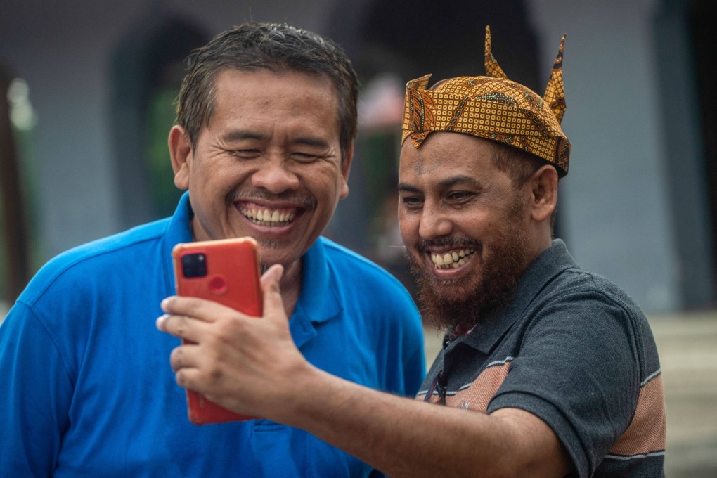 Hisyam bin Alizein (right), better known by his nom de guerre Umar Patek, makes a video call on Tuesday in Lamongan, Indonesia with his friend and former militant Ali Fauzi. Photo: AFP