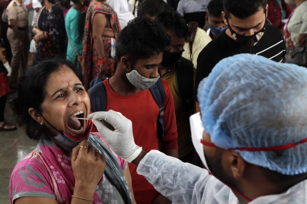 A health worker collects a swab sample from a traveler to test for Covid-19 at a train station in Mumbai, India. Photo: AP/File