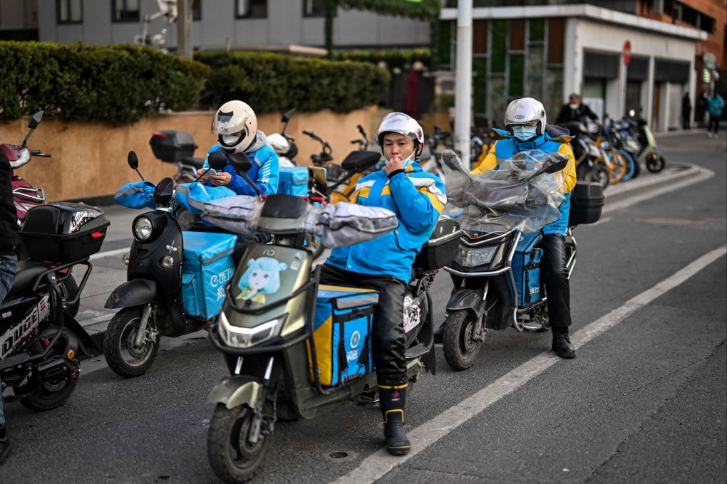 Delivery workers wait to cross a street in the Jing’an district in Shanghai on Monday. Photo: AFP