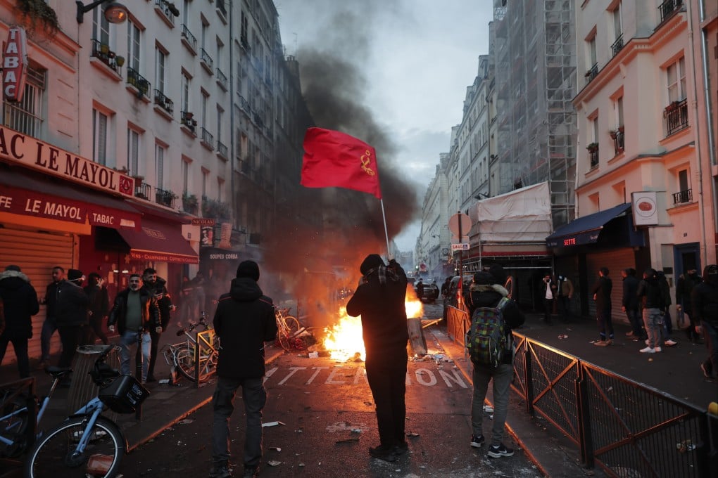 A members of the Kurdish community wave Kurdish communist flags next to a barricade on fire at the scene of a shooting in Paris on Friday. Photo: AP