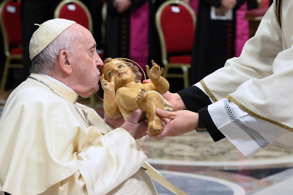 Pope Francis kisses a figurine of baby Jesus as he attends the Christmas Eve Mass at St Peter’s Basilica in the Vatican on Saturday. Photo: Vatican Media via AFP