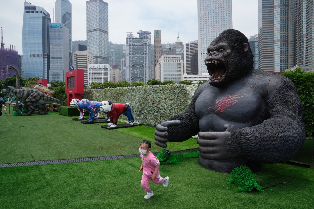 A girl wearing a mask runs away from a replica of a gorilla in a park in Hong Kong on May 9. Photo: AP