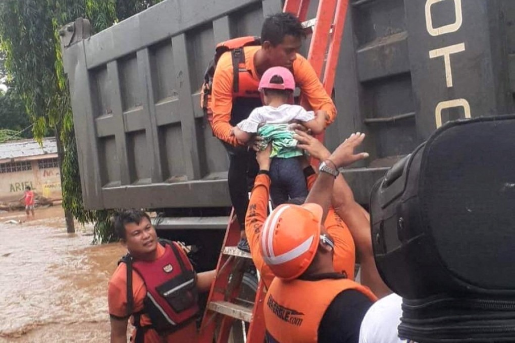 Rescuers lift a child to safety while helping people affected by floods in Plaridel, the Philippines’ Misamis Occidental province, on December 26. Photo: Philippine Coastguard Handout via Reuters