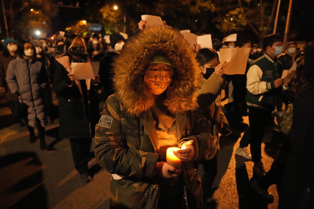 Protesters hold up blank papers and chant slogans as they march in protest against strict anti-virus measures in Beijing on November 27. Photo: AP