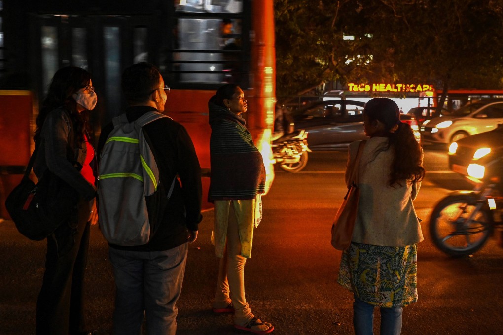 Women wait along a street to board a bus in New Delhi. Photo: AFP