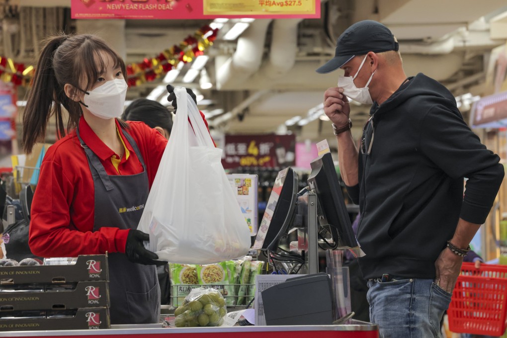 A grocery store cashier in Causeway Bay hands a customer a plastic bag on December 31 last year. Hongkongers have started paying HK$1 for each plastic bag at supermarkets, the first increase in the plastic bag levy in 13 years. Photo: Jelly Tse