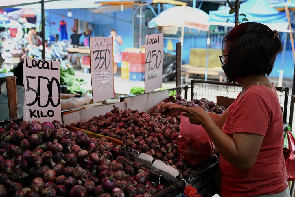 A woman buys onions at a market in Manila on Wednesday amid soaring prices for the food staple. Photo: AFP