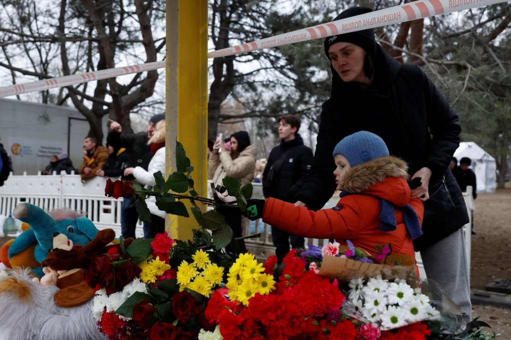 A woman and a child leave tributes near the site where a residential building was hit by a Russian missile in Dnipro, Ukraine. Photo: Reuters