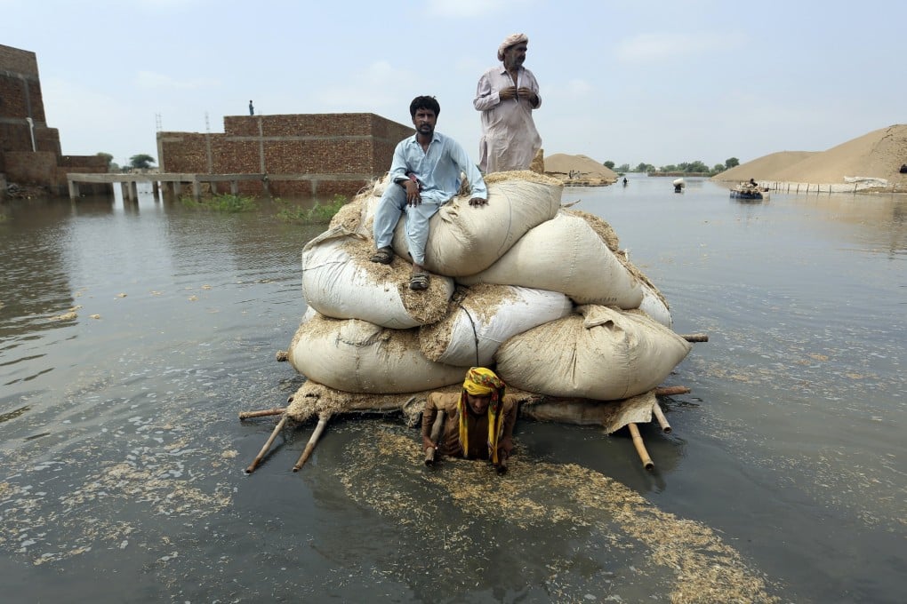 Flood victims from monsoon rain use a makeshift barge to carry hay for cattle, in Jaffarabad, in Pakistan’s southwestern Baluchistan province, on September 5, 2022. The flooding is just a preview of the climate consequences that are now impossible to avoid. Photo: AP