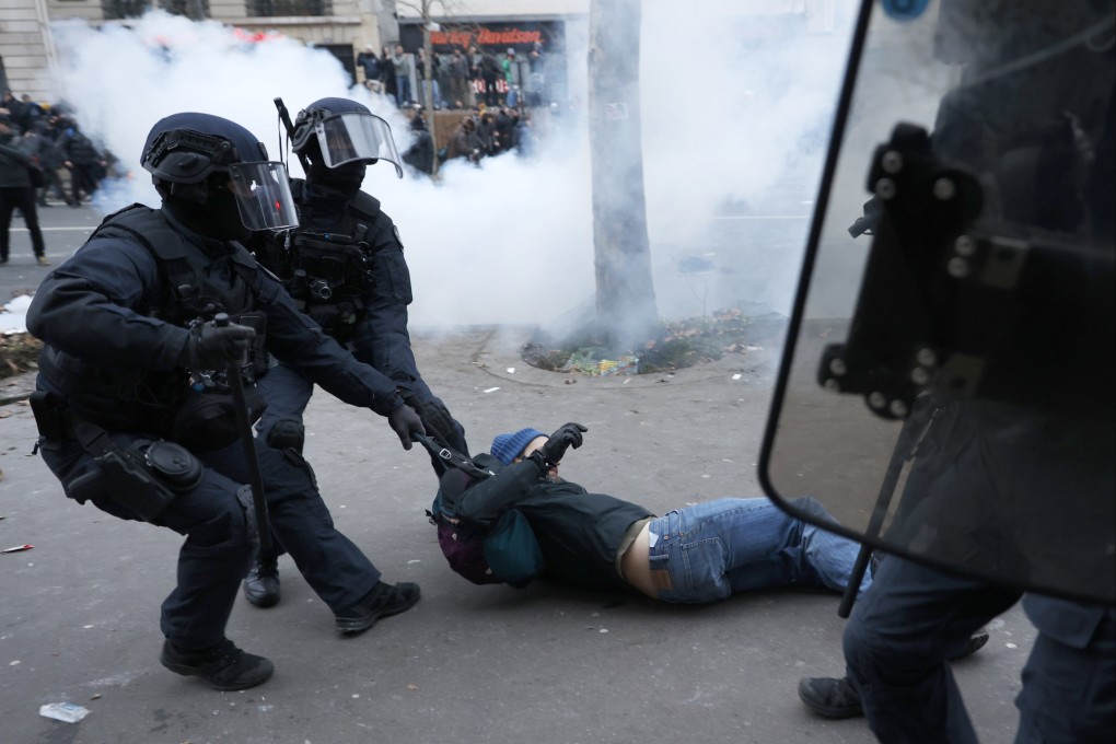 Riot police officers grab a protestor during a demonstration against pension changes in Paris. Photo: AP